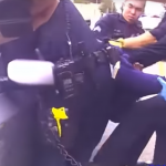 A still from the video shows Oakland police officers trying to pull Demouria Hogg from the car after he's been shot.