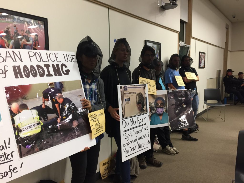 Protesters attended a July 9, 2019, Berkeley City Council meeting wearing spit hoods to call for a ban on them in the city. Photo: Berkeley Copwatch