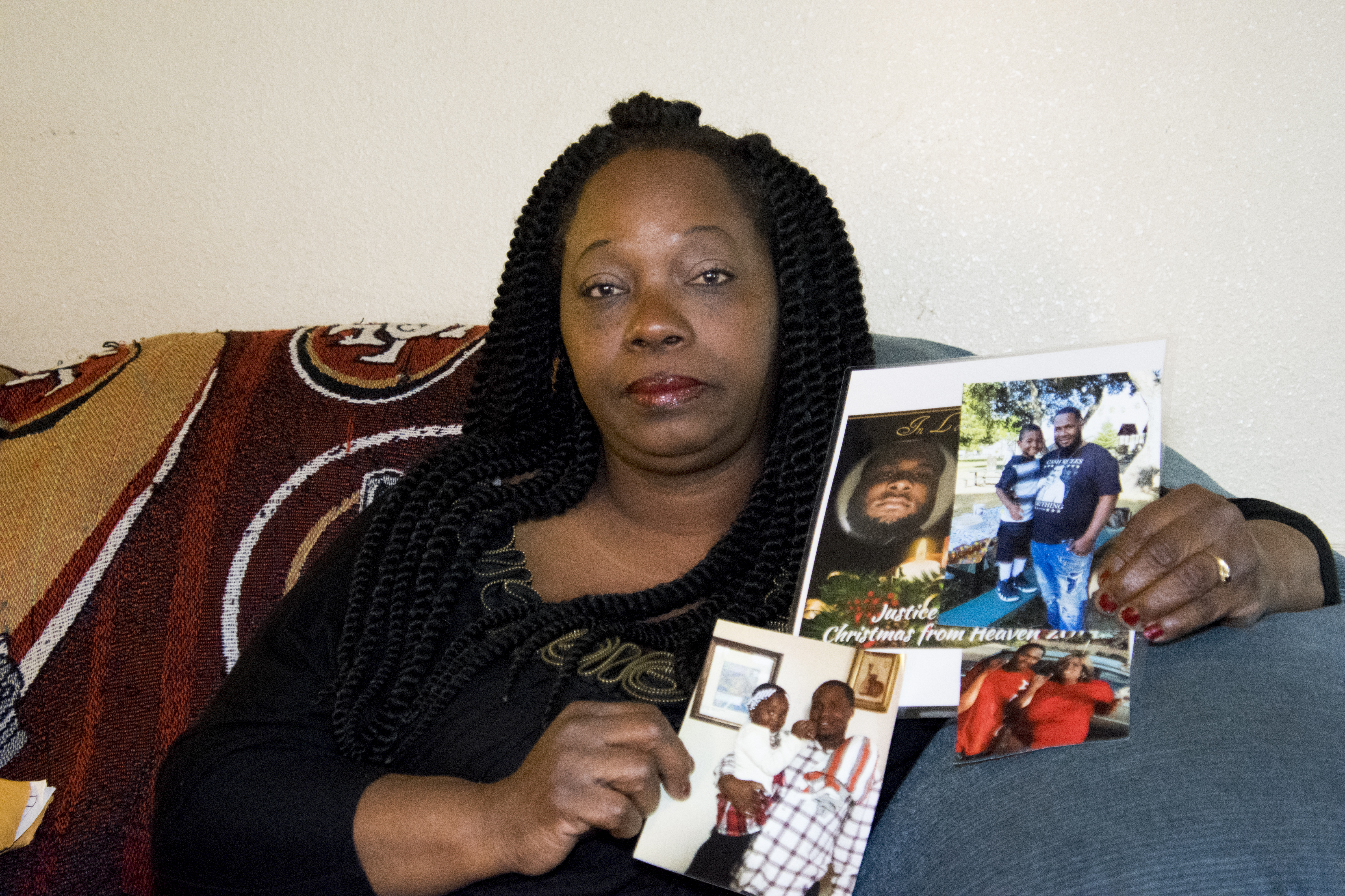 Barbara Doss holding photos of her son, Dujuan Armstrong, who died at Santa Rita Jail. Photo by Scott Morris.